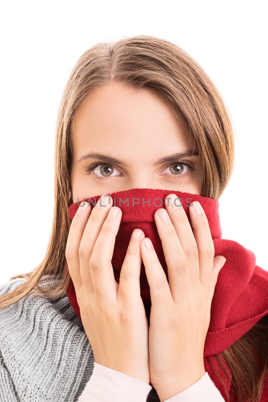 Close-up shot of a beautiful young girl in winter clothes, covering her mouth with a red scarf, isolated on white background.