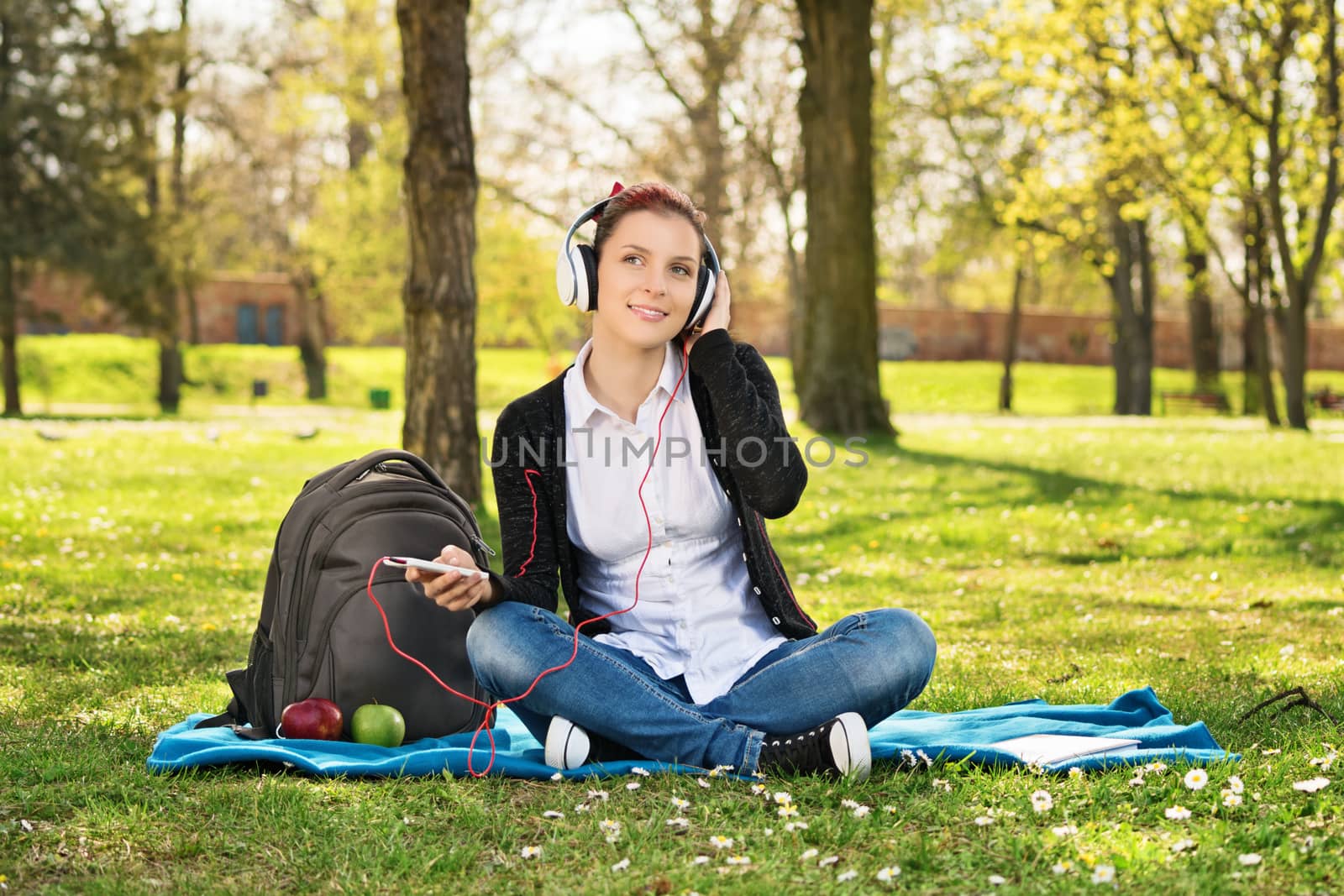 Girl student in park listening to music by Mendelex