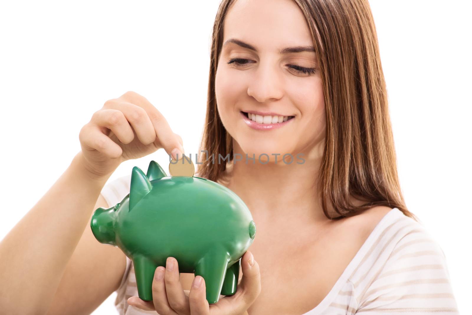 Young girl putting money in a piggy bank, isolated on white background.
