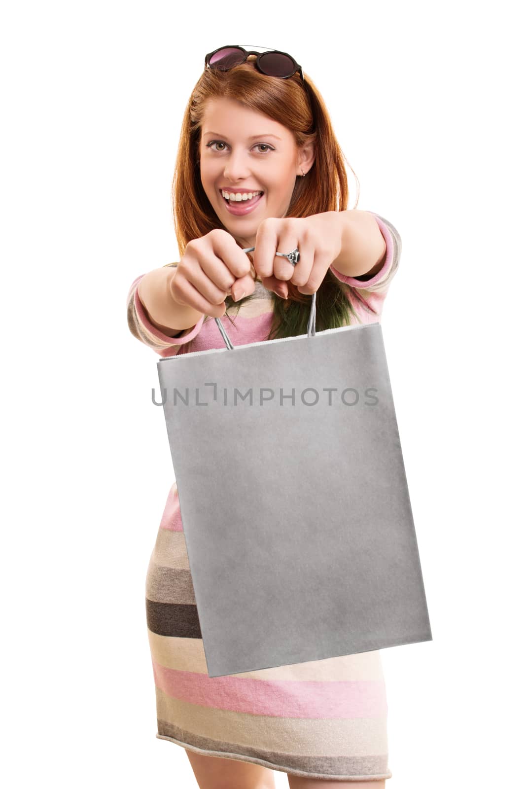 A portrait of a beautiful smiling girl, holding a shopping bag in front of her, isolated on white background.