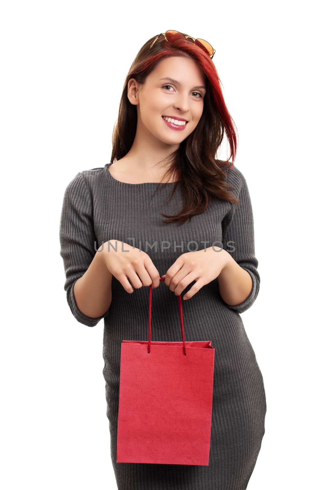 A portrait of a beautiful smiling young girl in a dress, holding a shopping bag, isolated on white background.