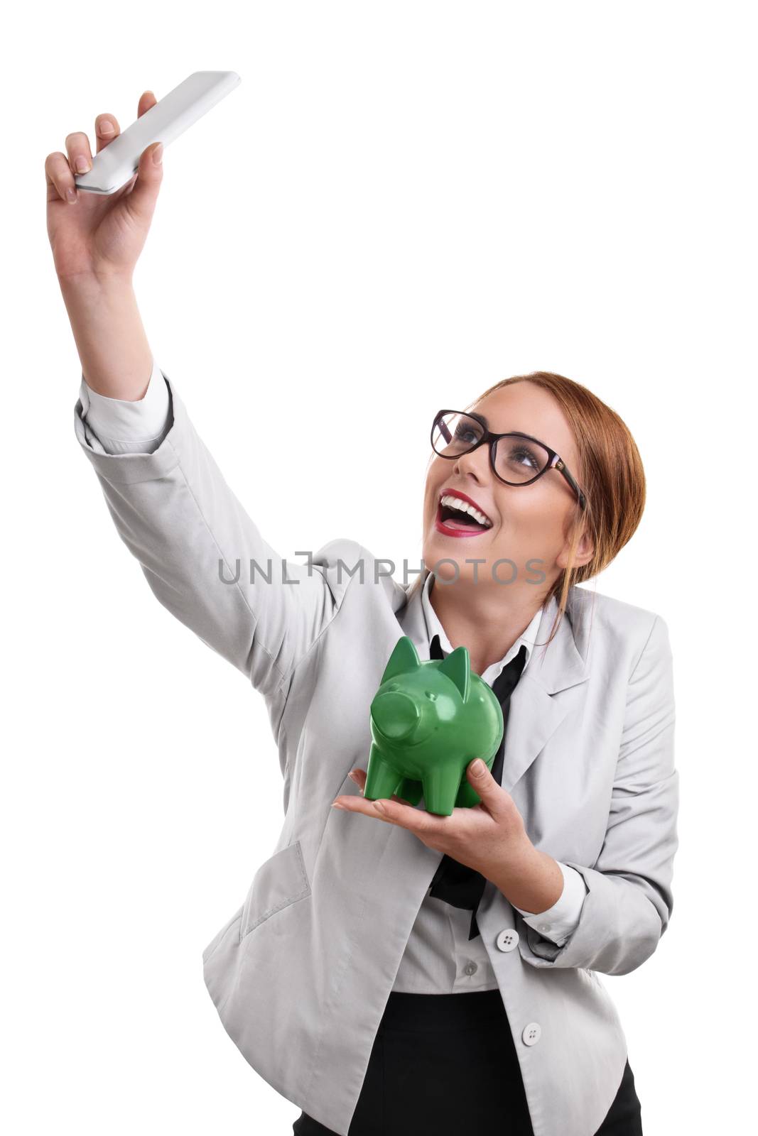 Beautiful young business woman taking a selfie with a piggy bank by Mendelex