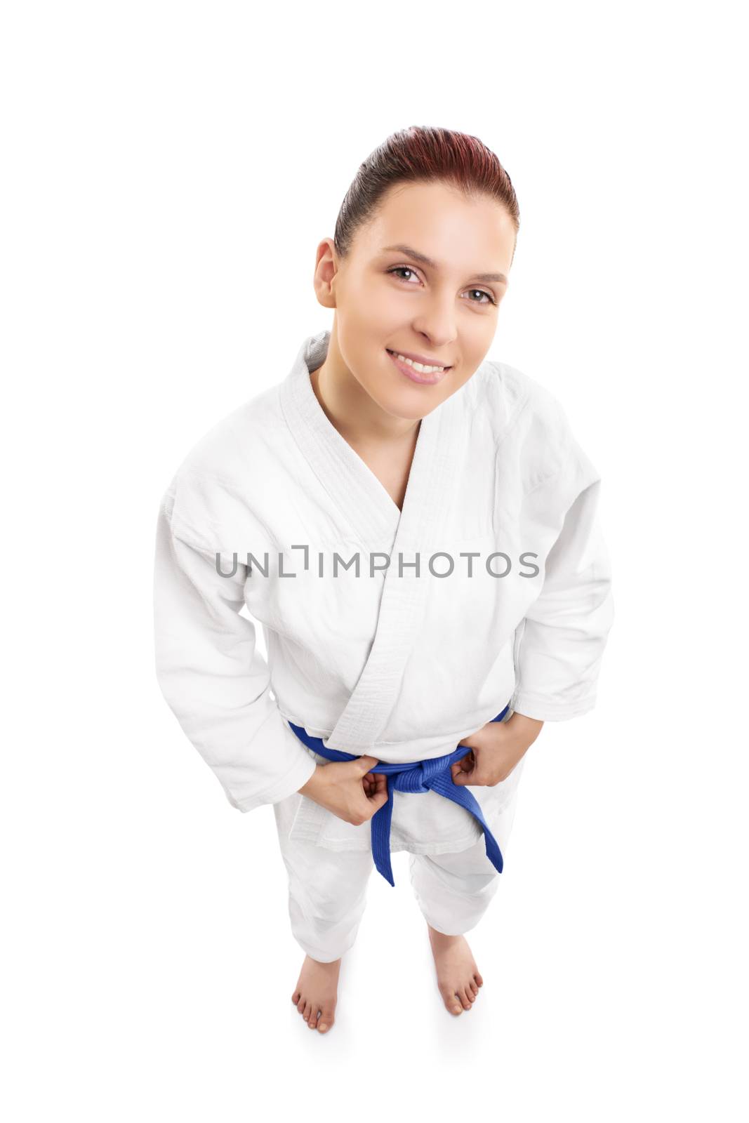 A portrait of a beautiful young female aikido fighter smiling, from top, isolated on white background.