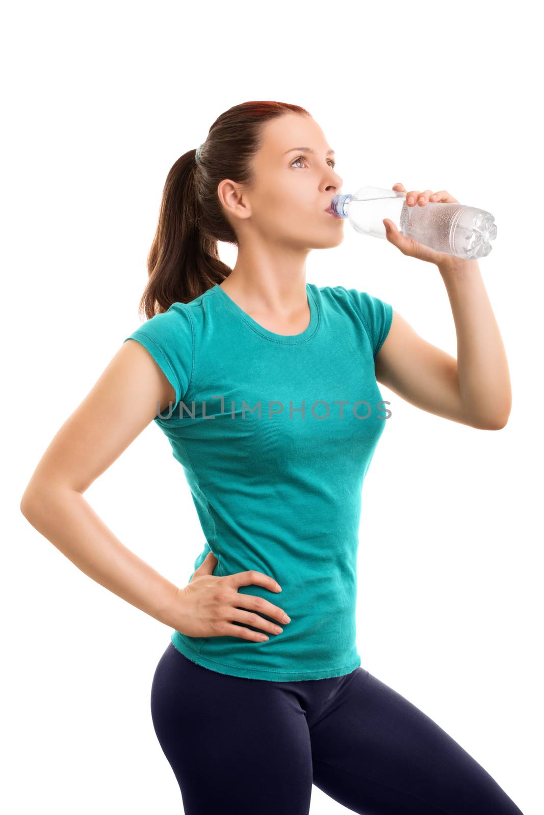 Keep yourself well hydrated while exercising. Beautiful young girl drinking water after her workout, isolated on white background.