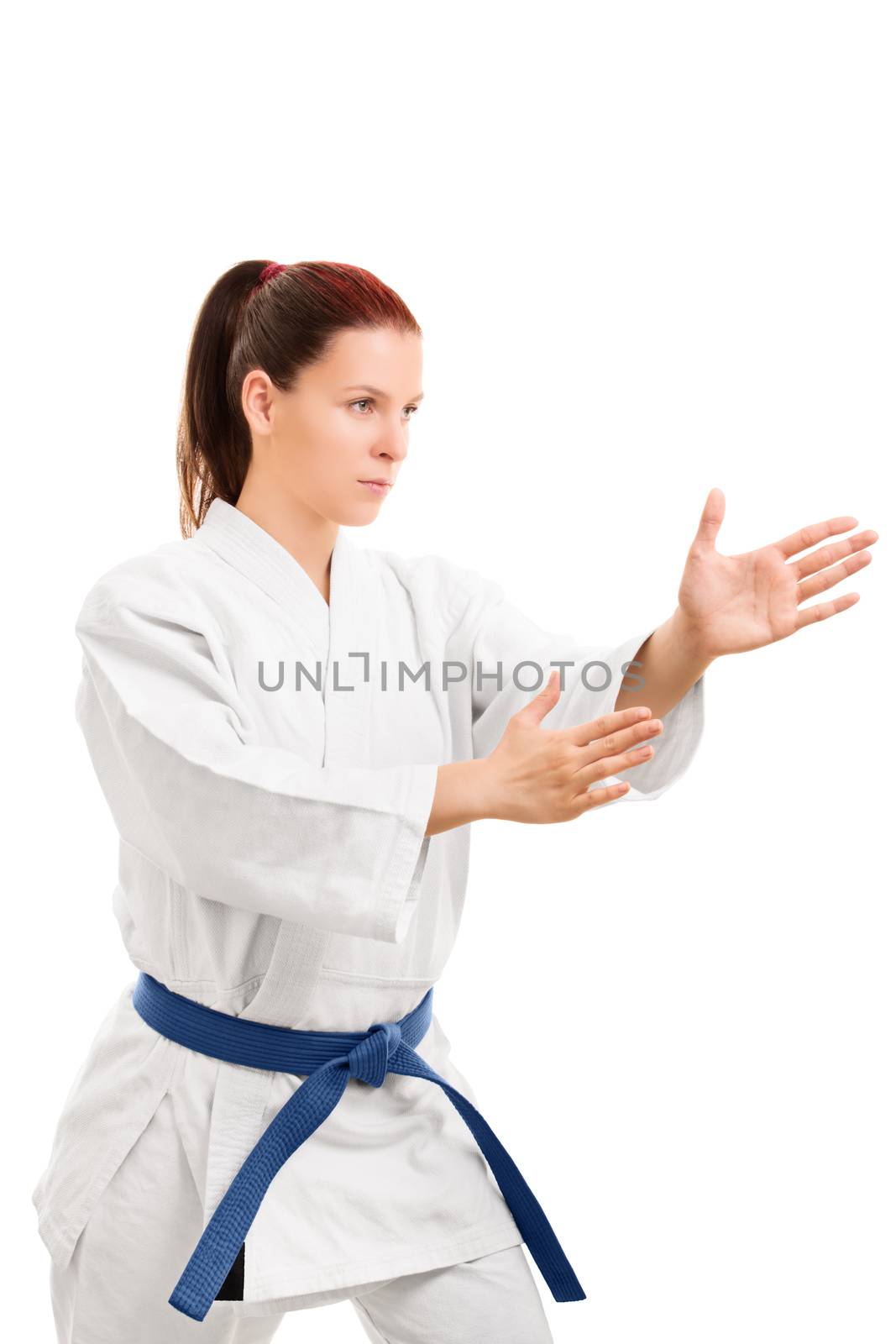A portrait of a young girl in a kimono with blue belt in a fighting stance, isolated on white background.