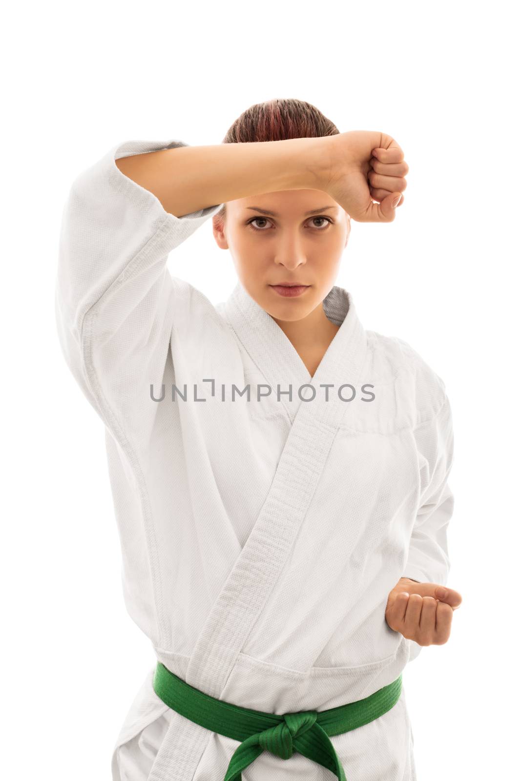 Blocked. Young girl in kimono with green belt taking defensive stance, isolated on white background.