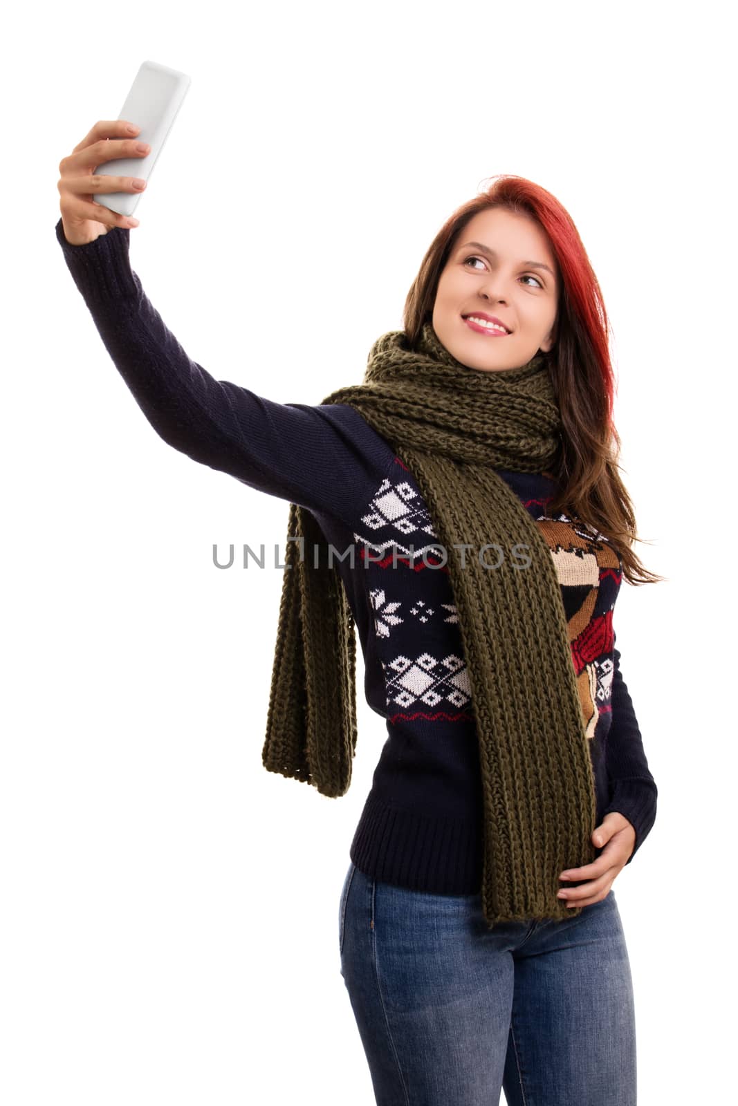 A portrait of a beautiful young girl in winter clothes taking a selfie, isolated on white background.