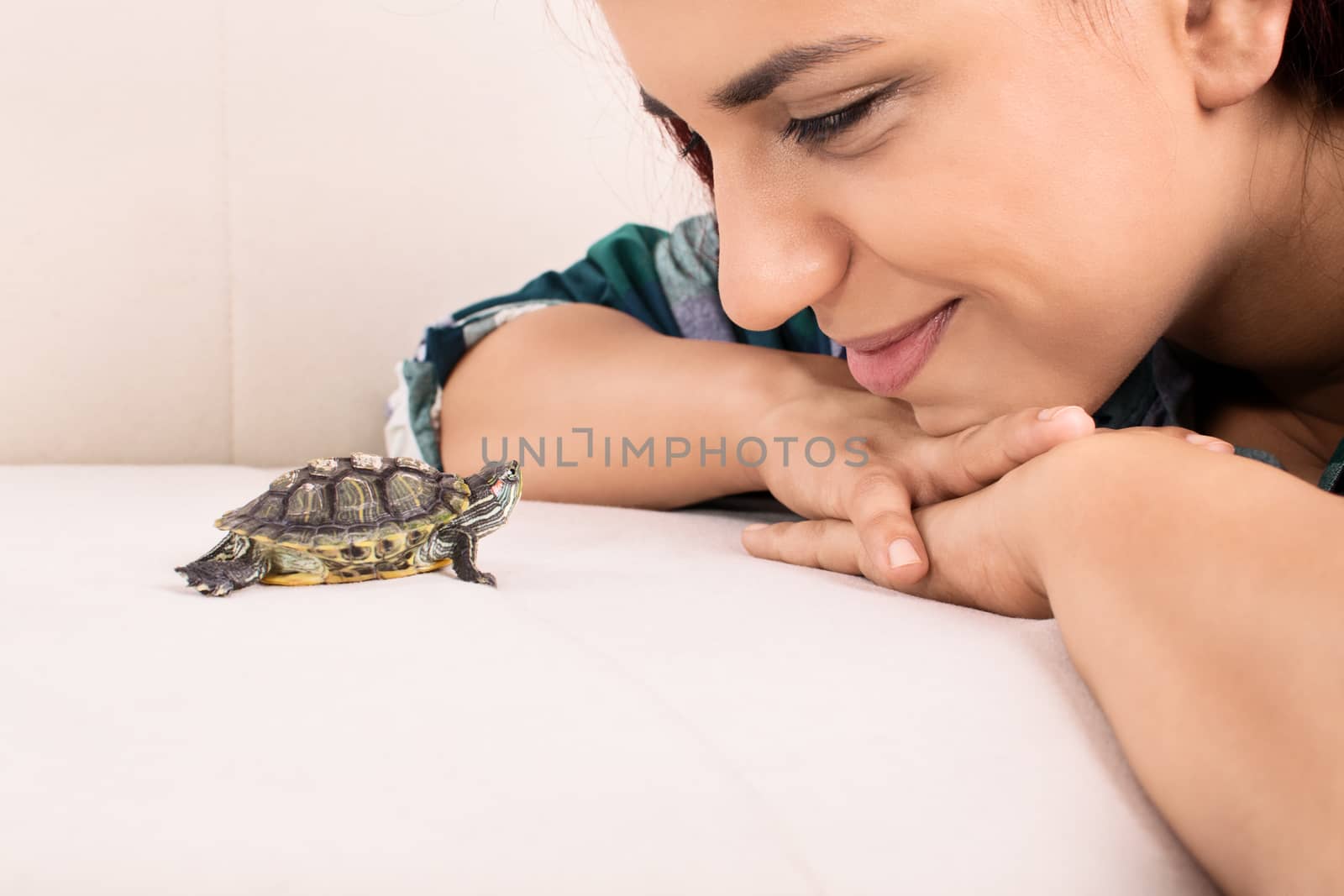 Close up shot of a beautiful young girl looking at a little turtle.