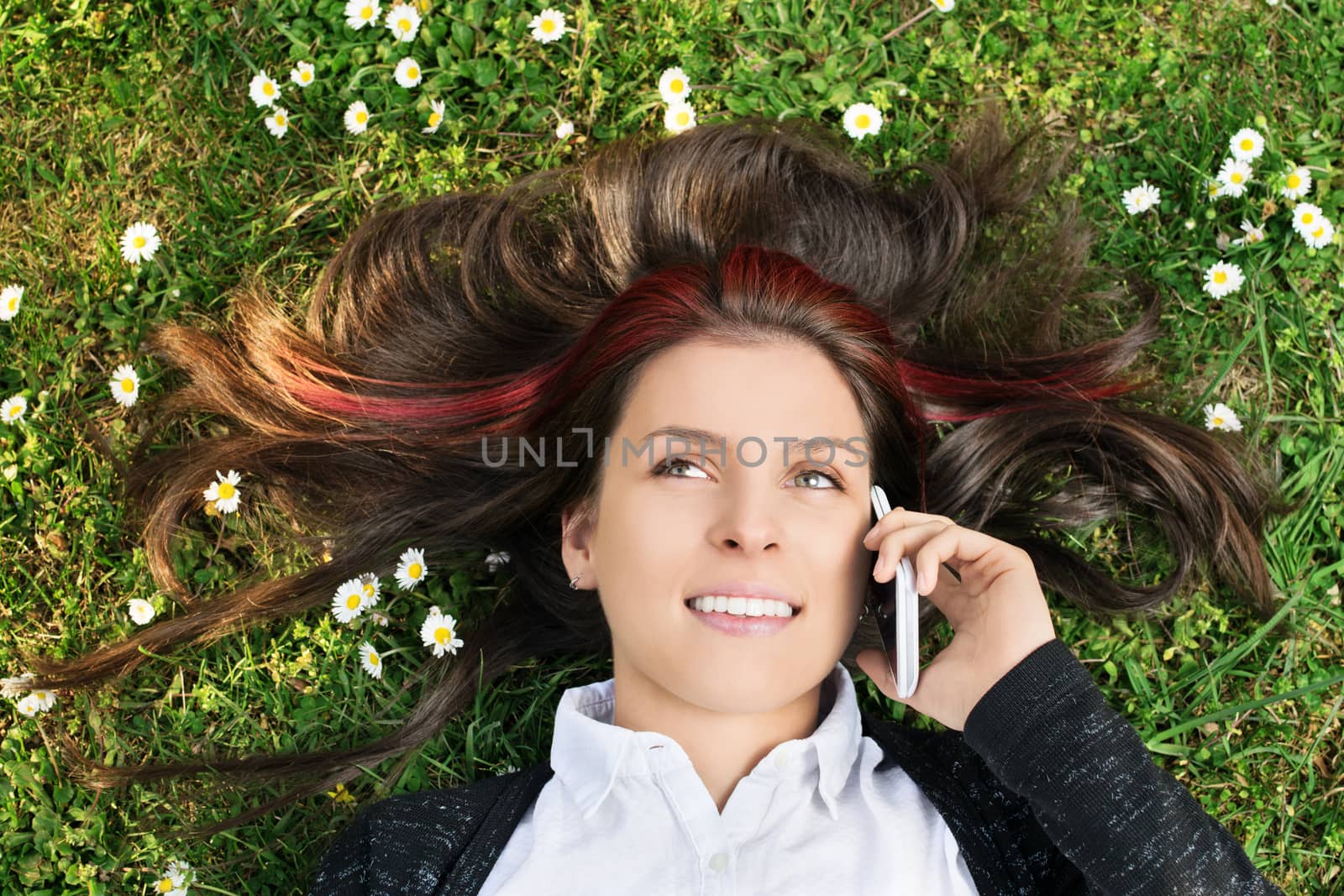 Young girl lying on a meadow talking on the phone by Mendelex