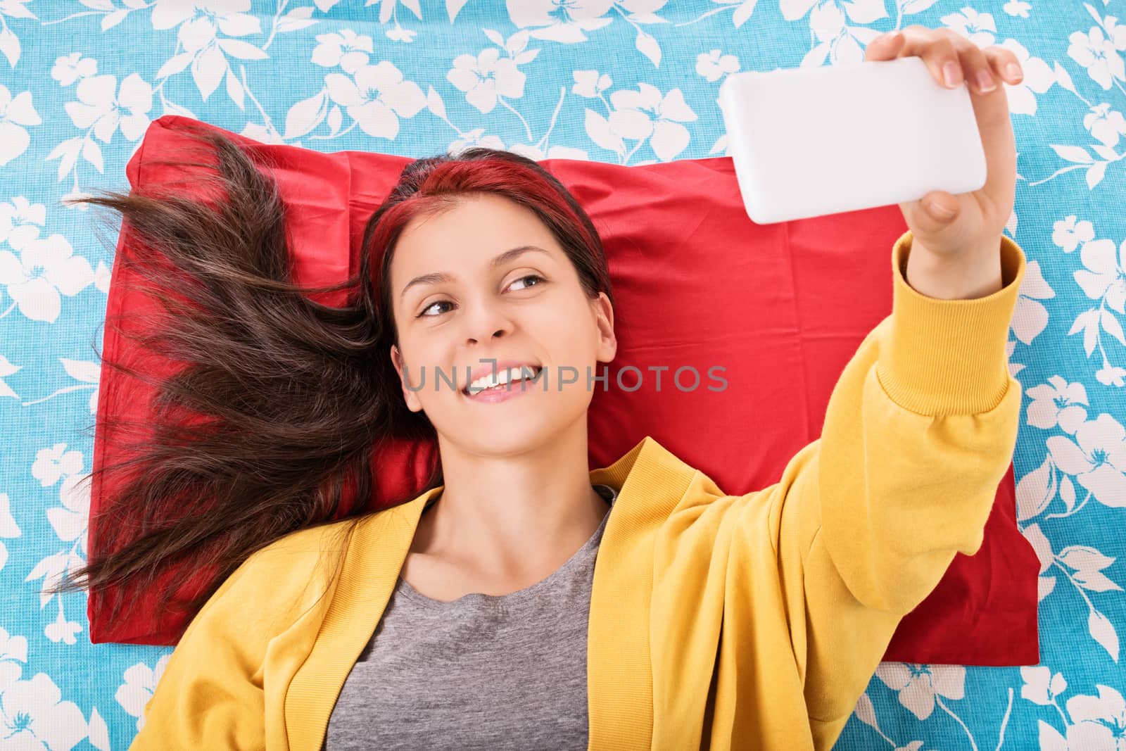 Young girl taking a selfie on her bed by Mendelex