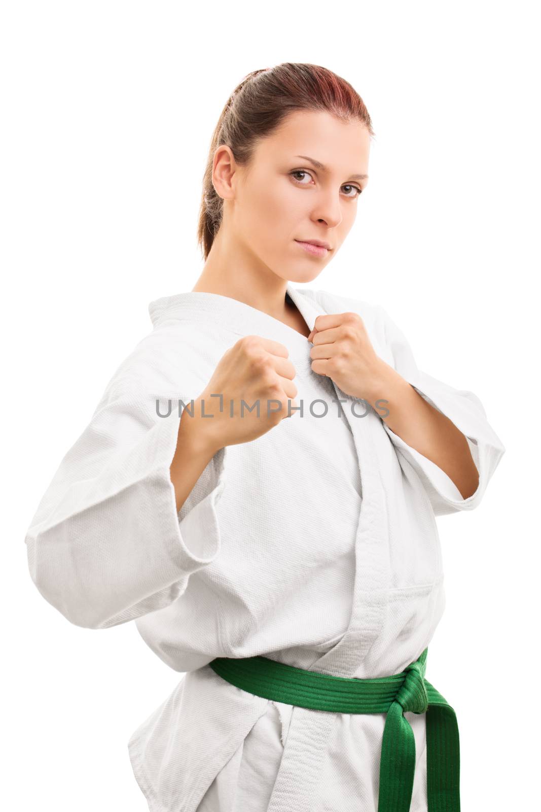 Ready to engage. Beautiful young in a kimono with green belt standing in a combat stance, isolated on white background.