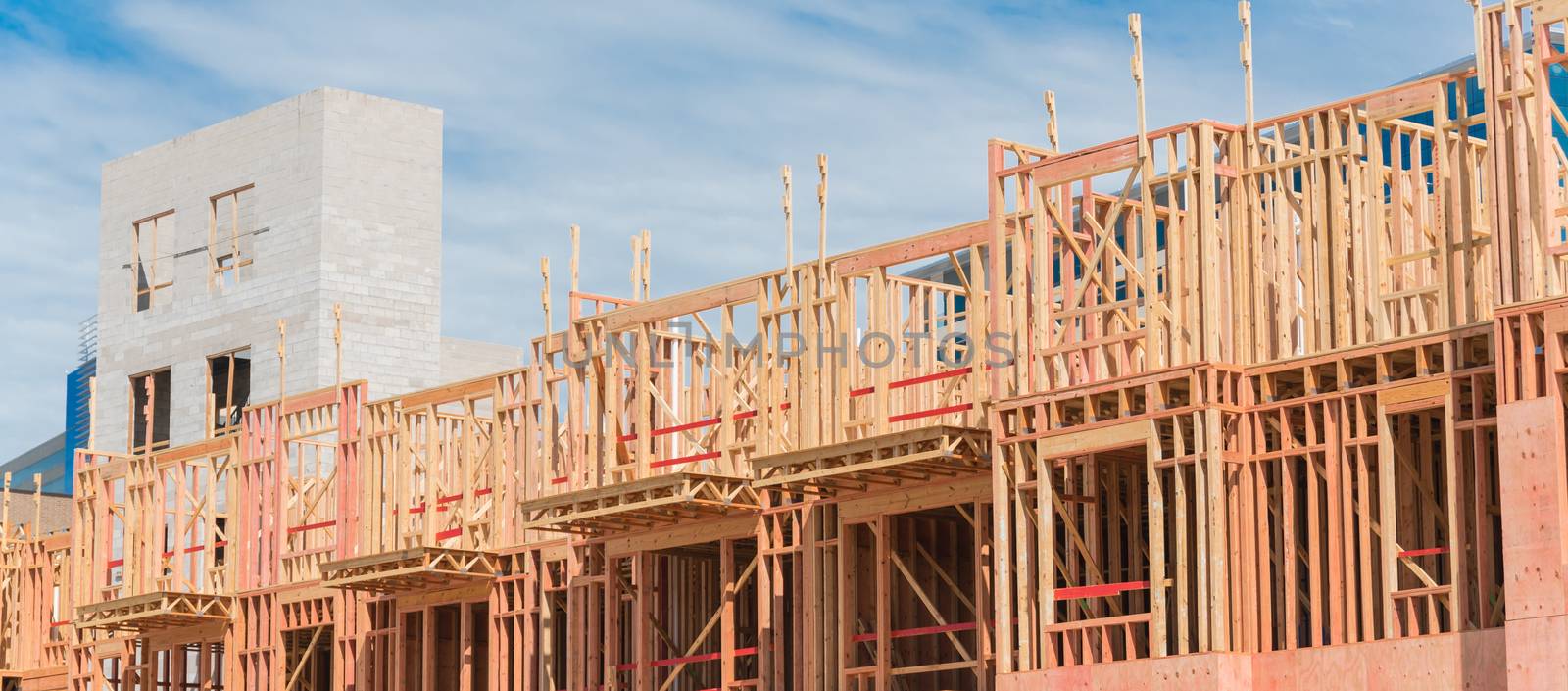 Panorama view multistory condominium under construction with wooden lumber timber framework and concrete elevator shaft. Modern apartment complex rental living space near Dallas, Texas