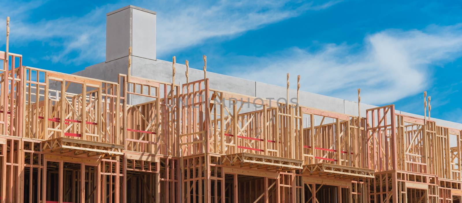 Panorama view multistory condominium under construction with wooden lumber timber framework and concrete elevator shaft. Modern apartment complex rental living space near Dallas, Texas