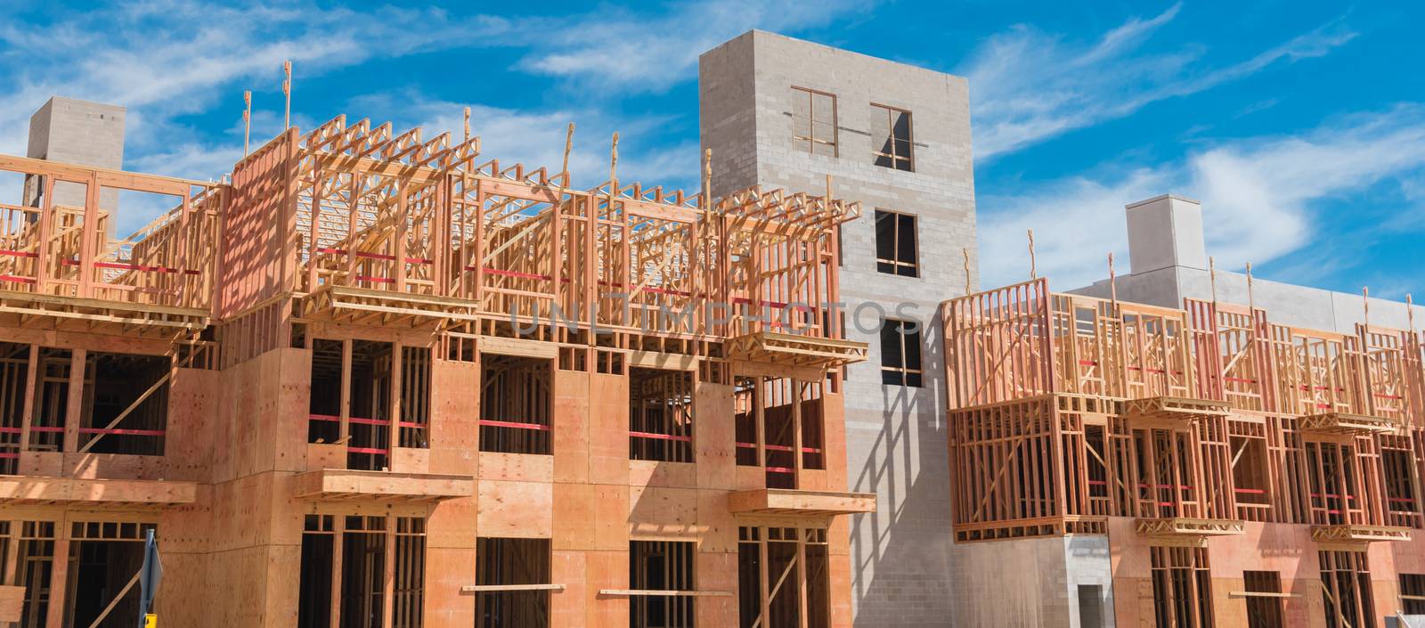 Panorama view multistory condominium under construction with wooden lumber timber framework and concrete elevator shaft. Modern apartment complex rental living space near Dallas, Texas