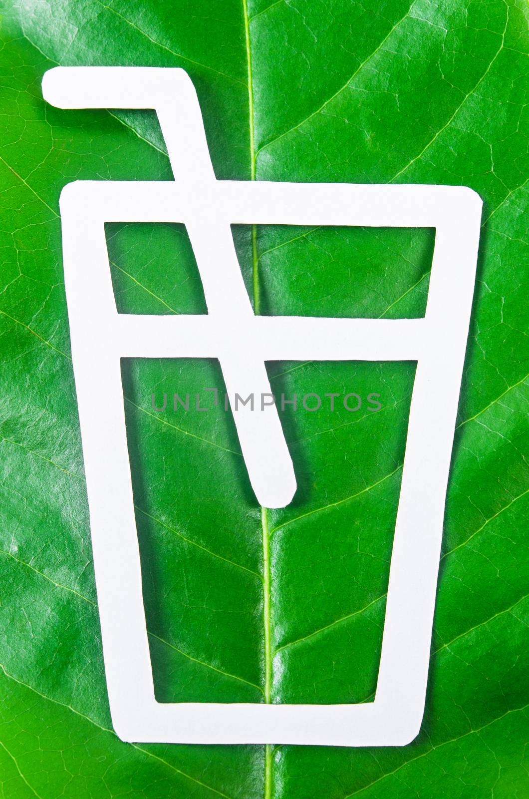 glass ans straw made from paper cut out on leaf green tree. Biodegradable package concept.