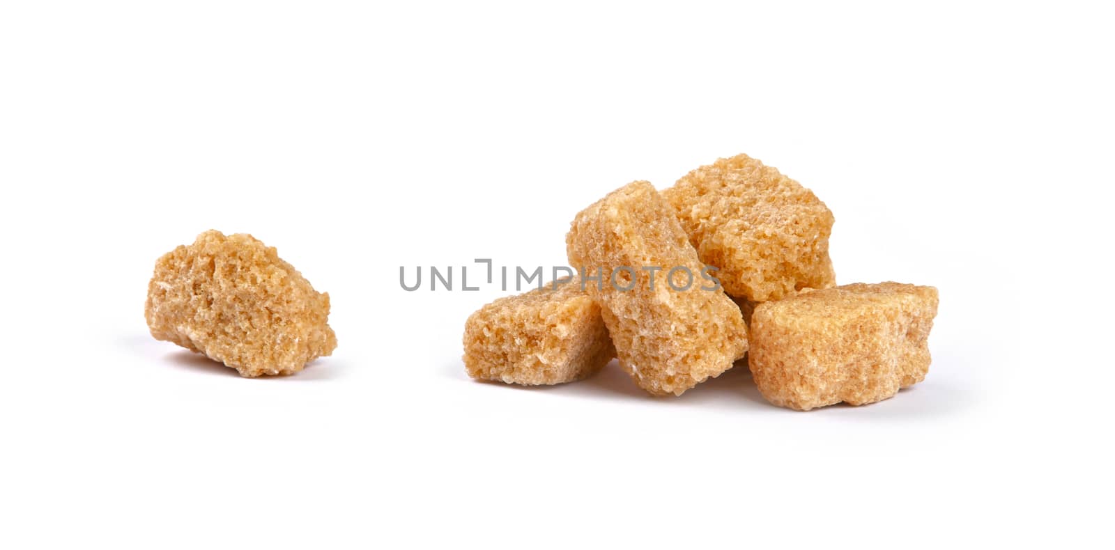 Close up group of brown demerara sugar cubes isolated on white background, side view