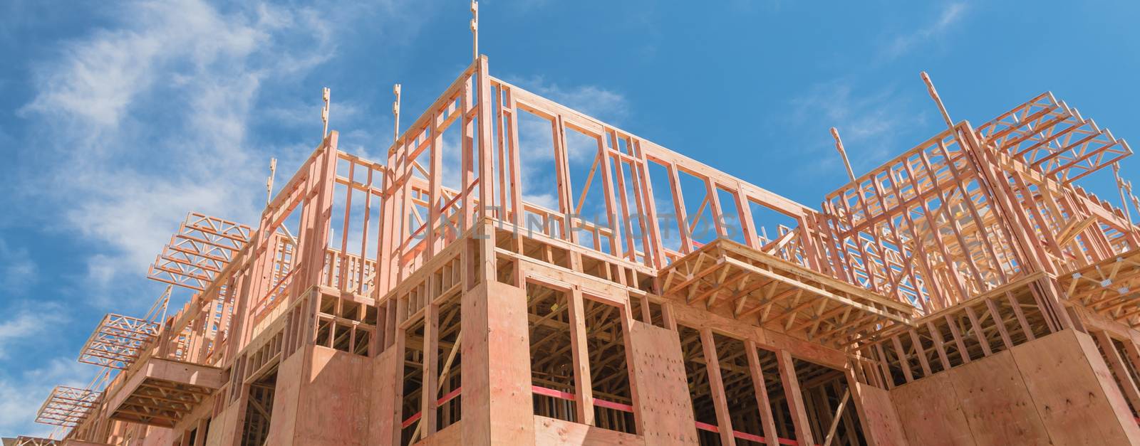 Panorama view low angle view of modern condominium building with large patio under construction near North Dallas, Texas. Wooden house with timber framing, truss, joist, beam close-up cloud blue sky