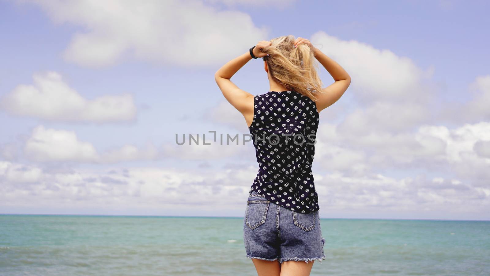Outdoor summer portrait of young pretty woman looking to the ocean at tropical beach, enjoy her freedom and fresh air