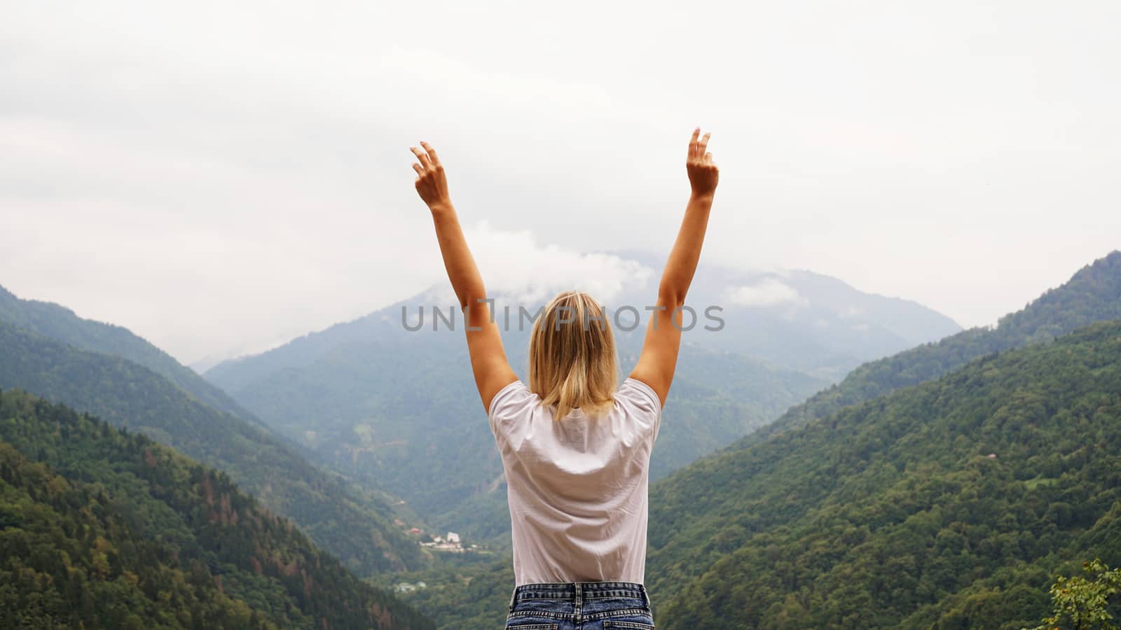 Cheering woman hiker open arms at mountain peak by natali_brill