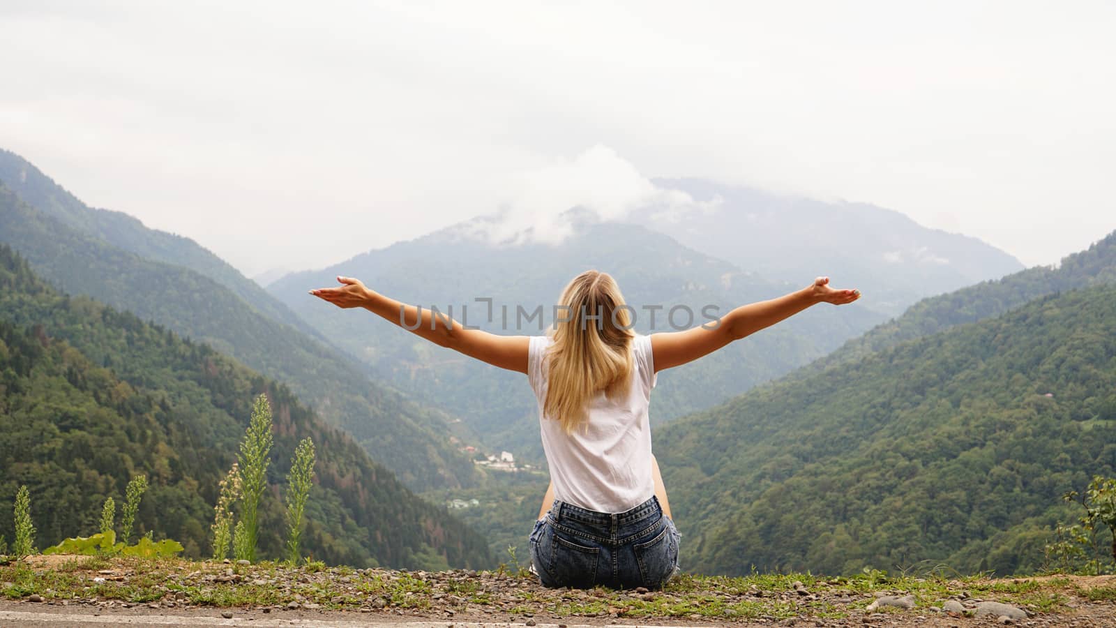 Cheering woman hiker open arms at mountain peak by natali_brill