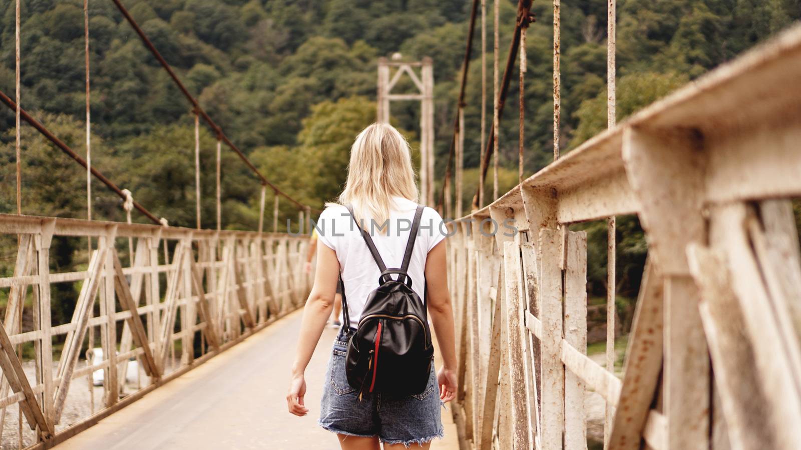 Beautiful girls traveling, walking on a bridge while they are enjoying the beautiful view of mountains