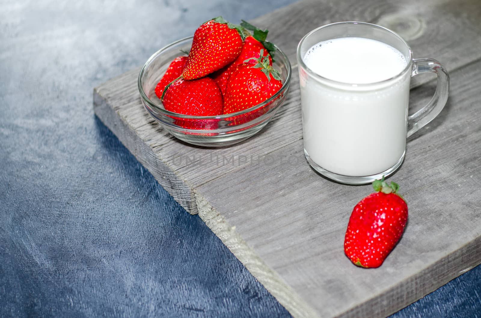 Fresh strawberries and milkshake on a wooden on wooden boards.