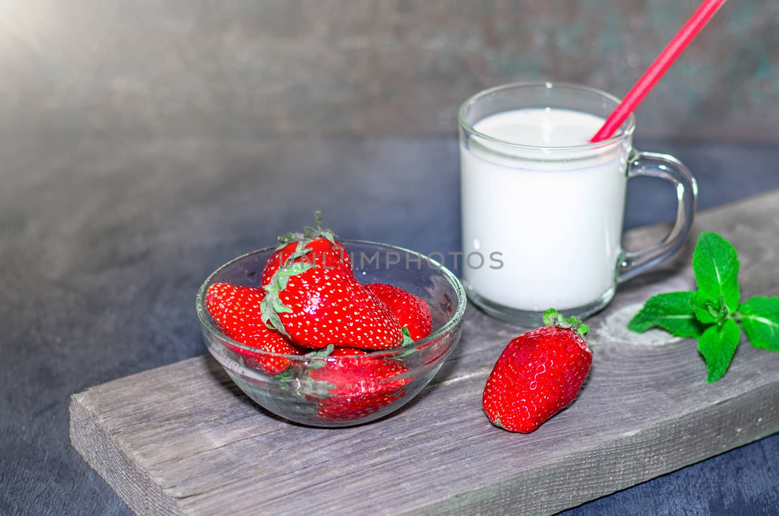 Fresh strawberries and milkshake on a wooden on wooden boards.