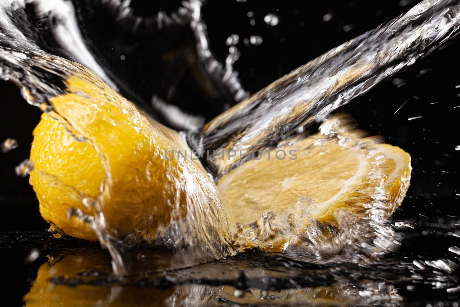 Lemon and pouring water on a black glass background