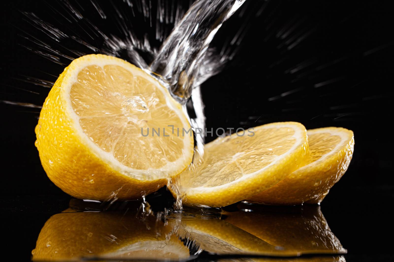 Lemon and pouring water on a black glass background
