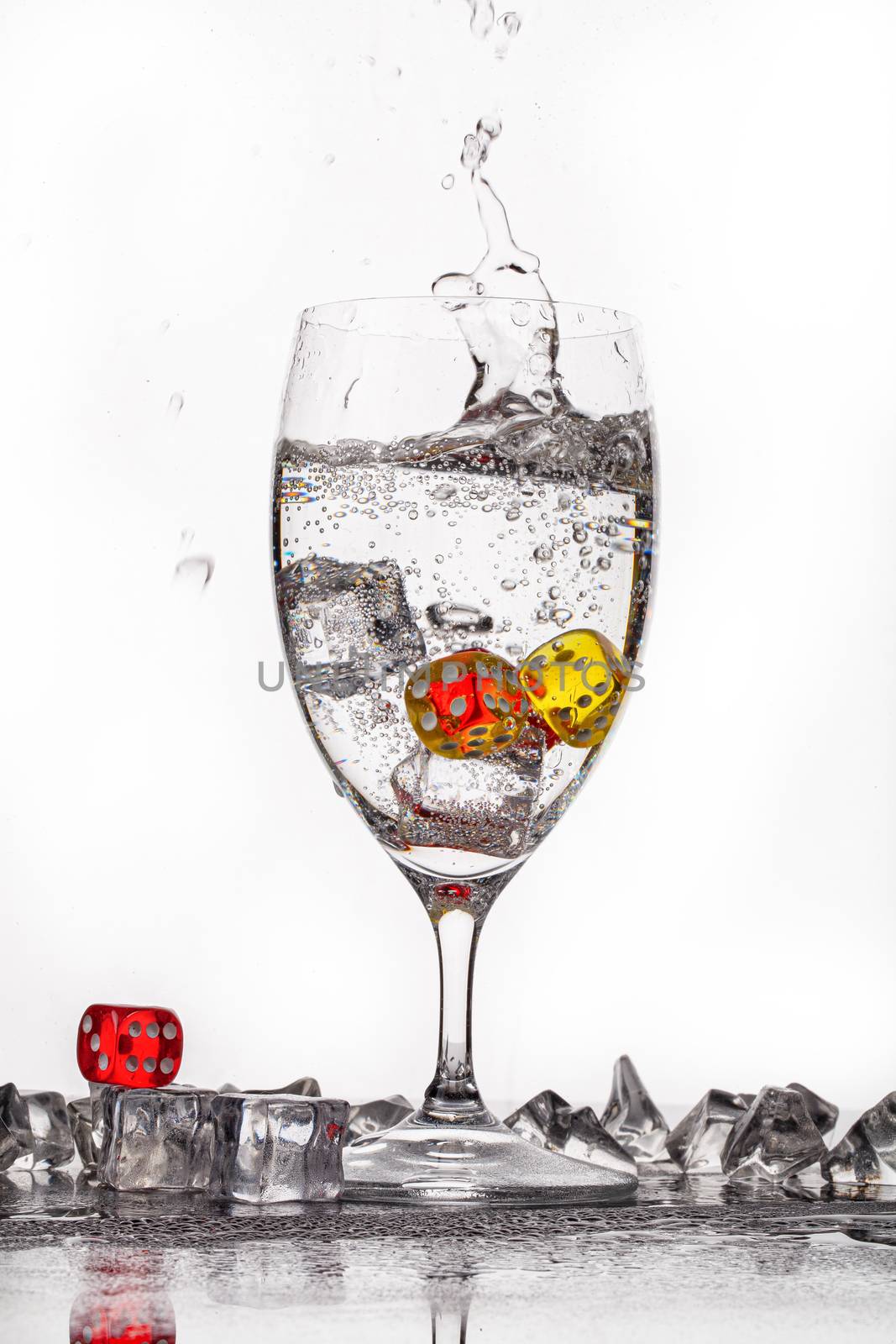 Dices, crystals of ice and glass of water ona glass backround