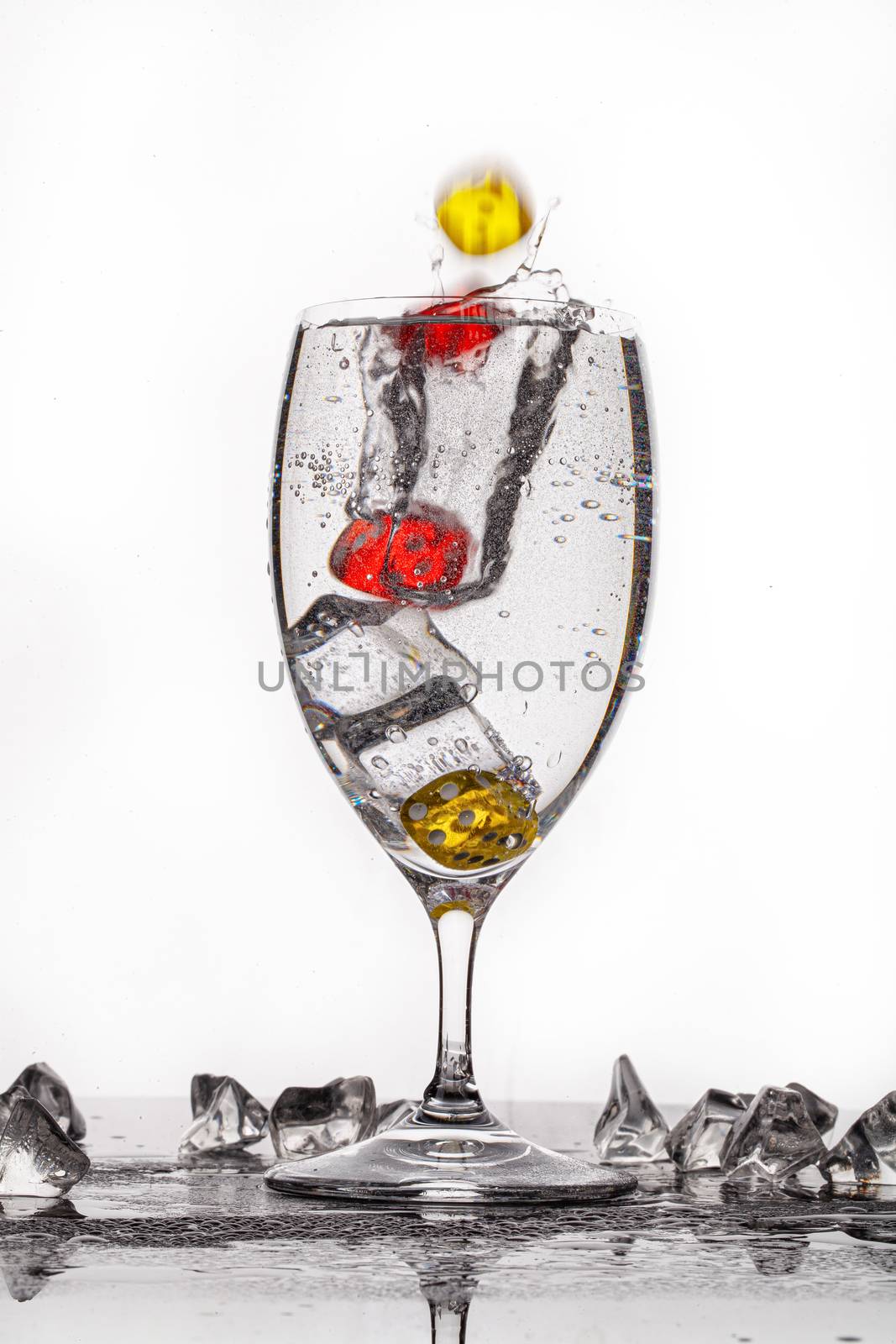 Dices, crystals of ice and glass of water ona glass backround