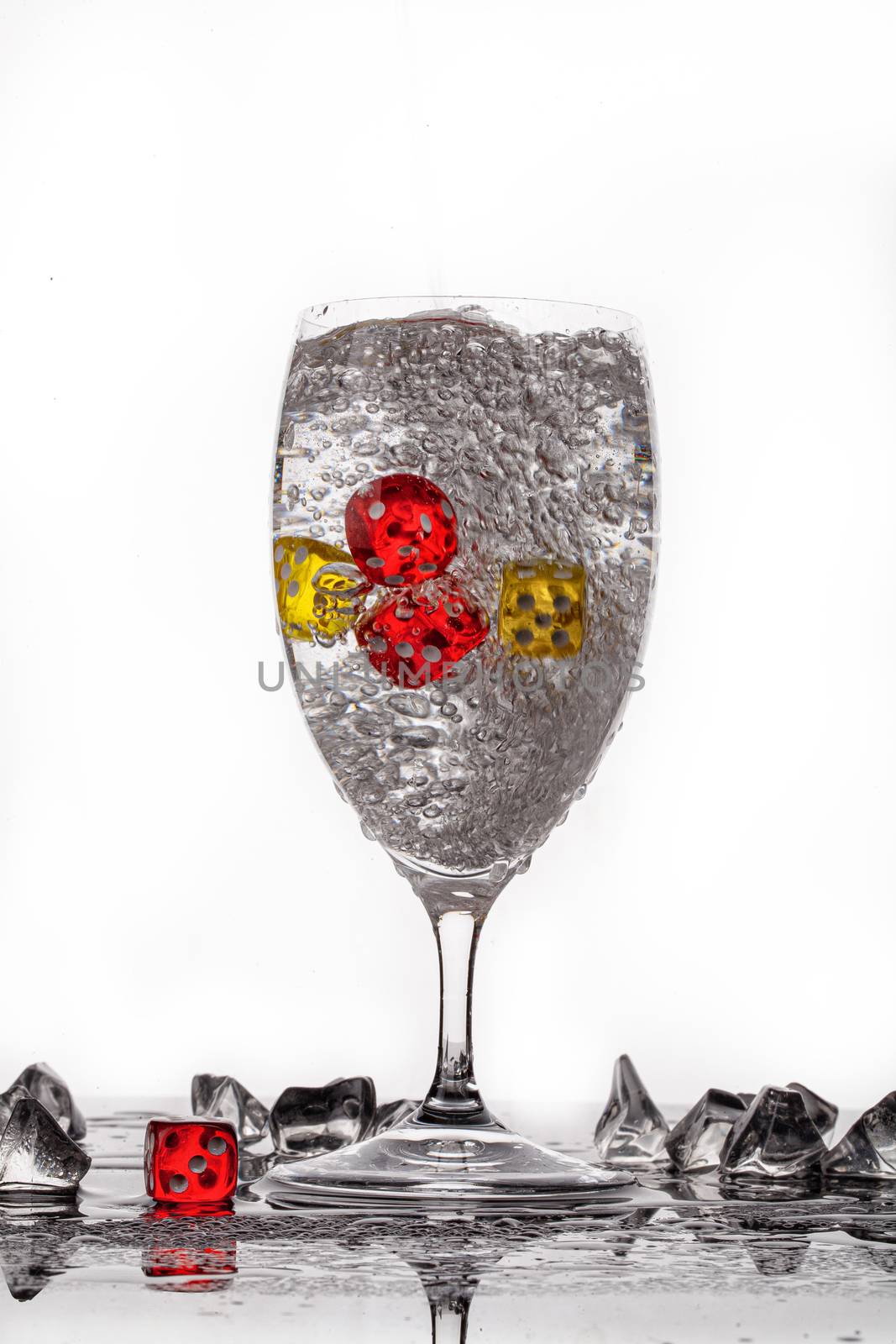 Dices, crystals of ice and glass of water ona glass backround