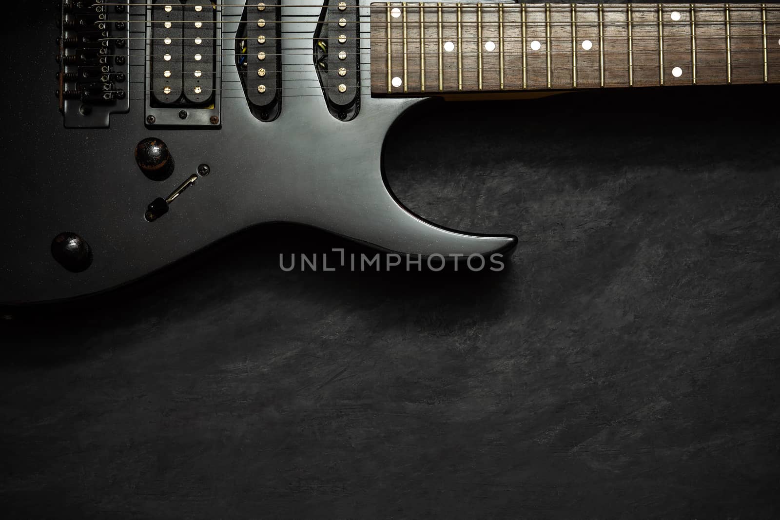 Black electric guitar on black cement floor. Top view and copy space for text. Concept of rock music.