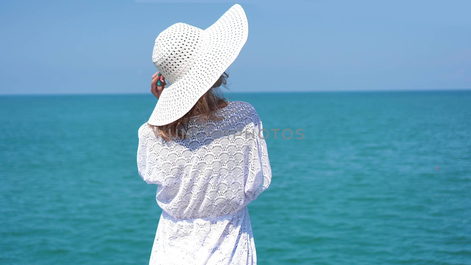 Young woman standing on sand near sea and holding a hat by natali_brill