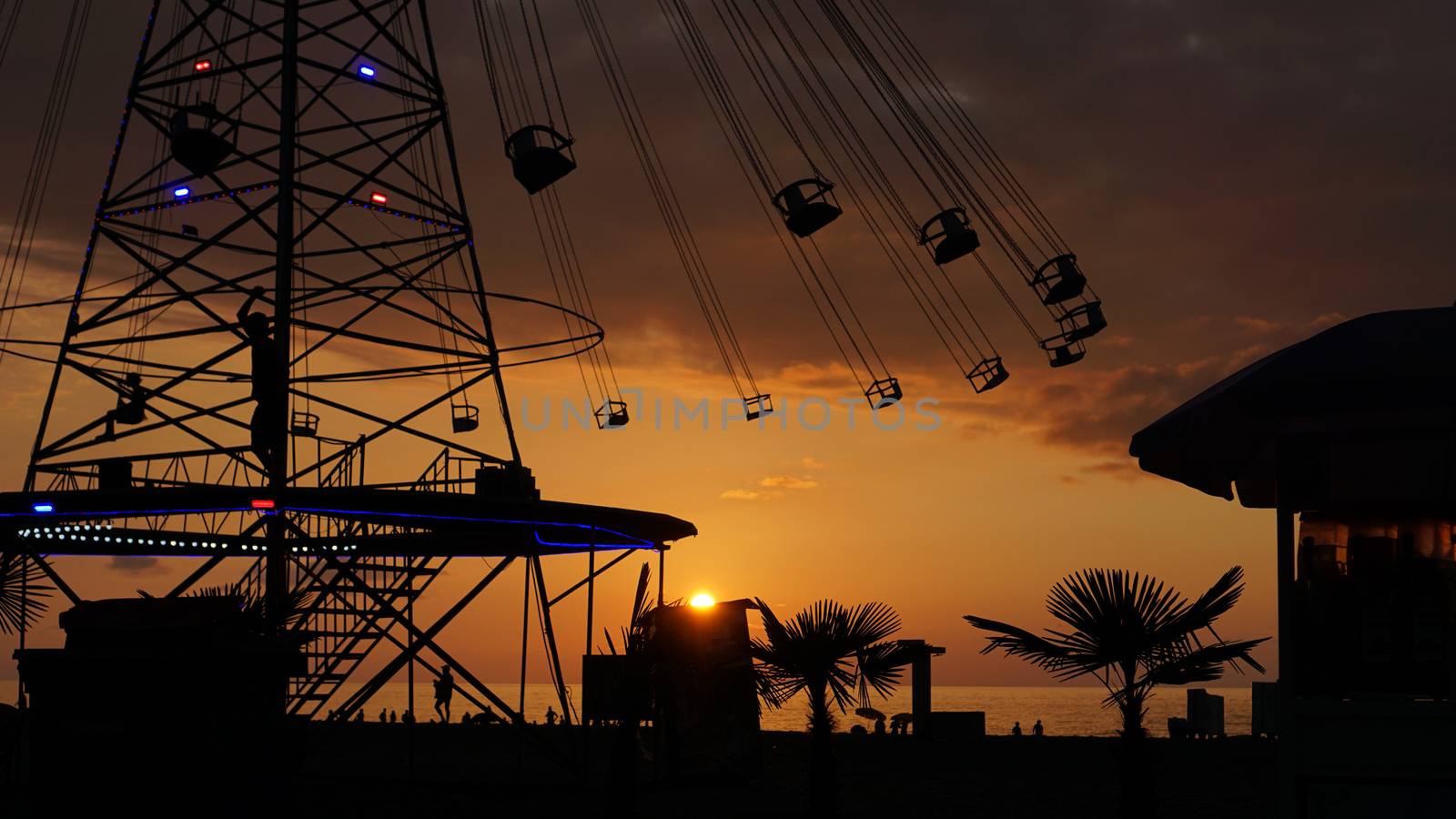 Swinging carousel roundabout chain ride at sunset by natali_brill