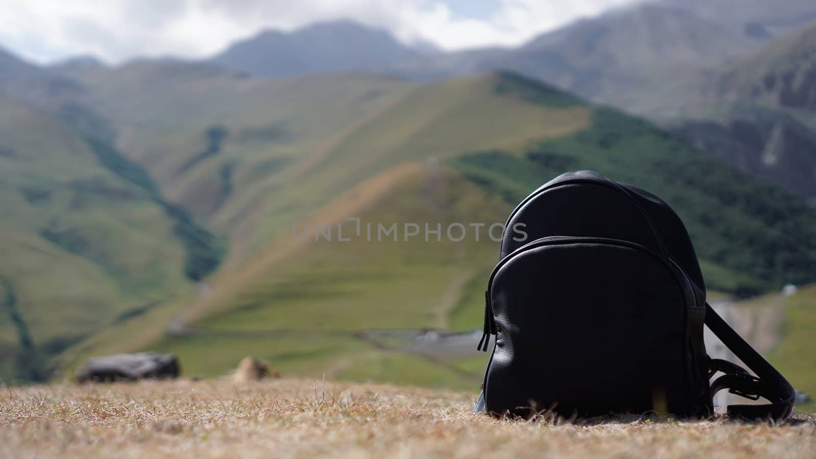 Black backpack on the background of Mount Kazbegi. Traveling in Georgia by natali_brill