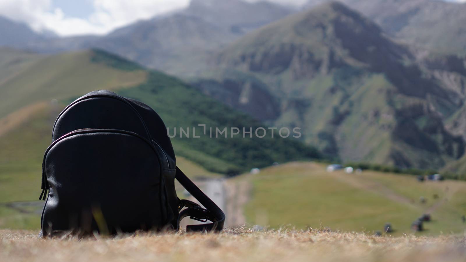 Black backpack on the background of Mount Kazbegi. Traveling in Georgia by natali_brill