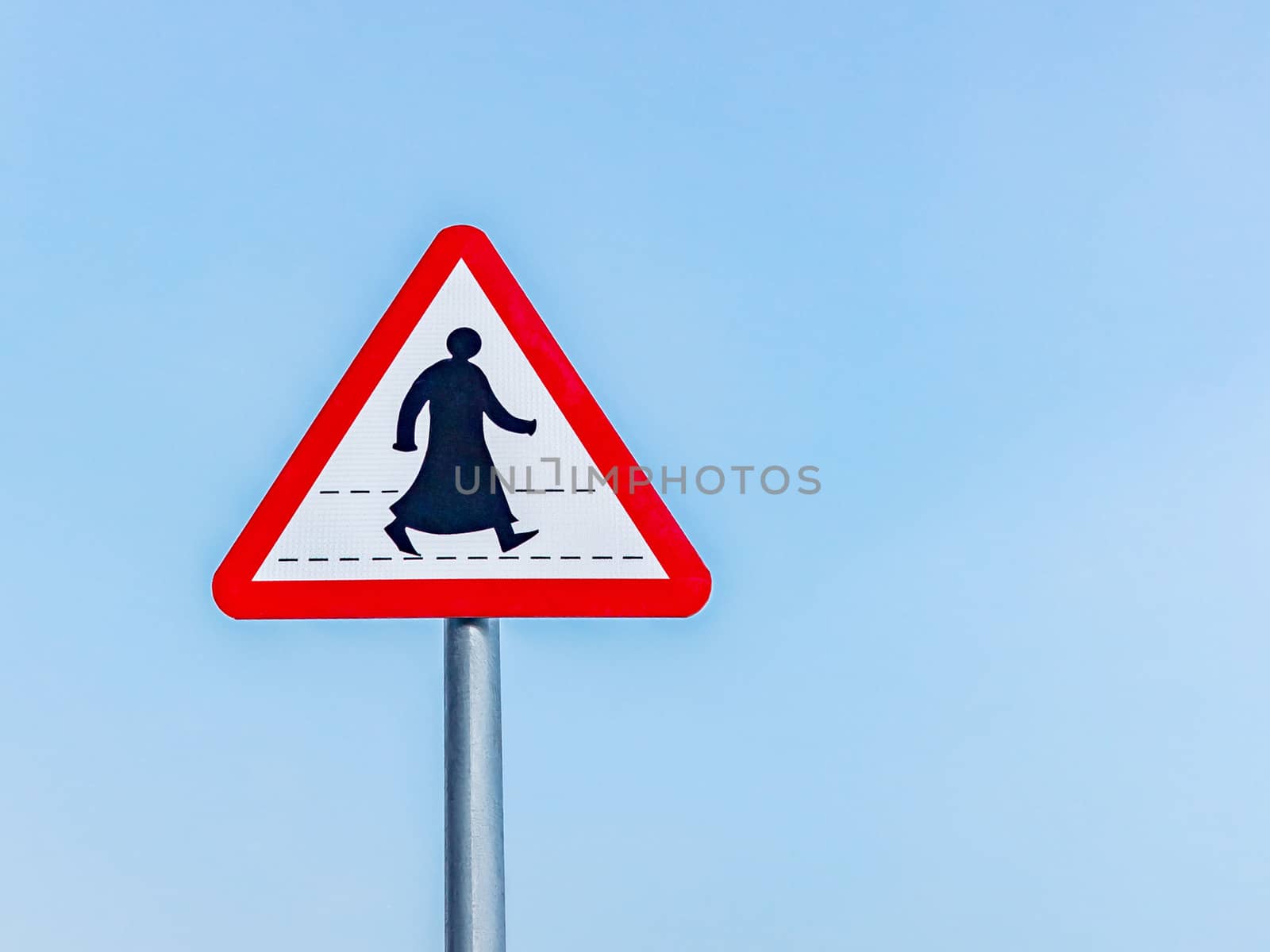 Sign prohibiting traffic for pedestrians in a southern Arab country, a silhouette of a pedestrian in traditional clothes, against a blue sky.