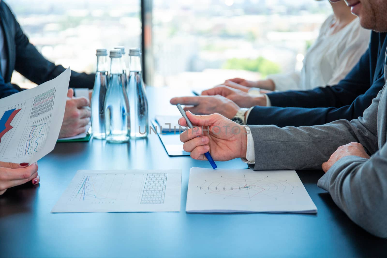 Business people discussing documents at workplace in office sitting around the table