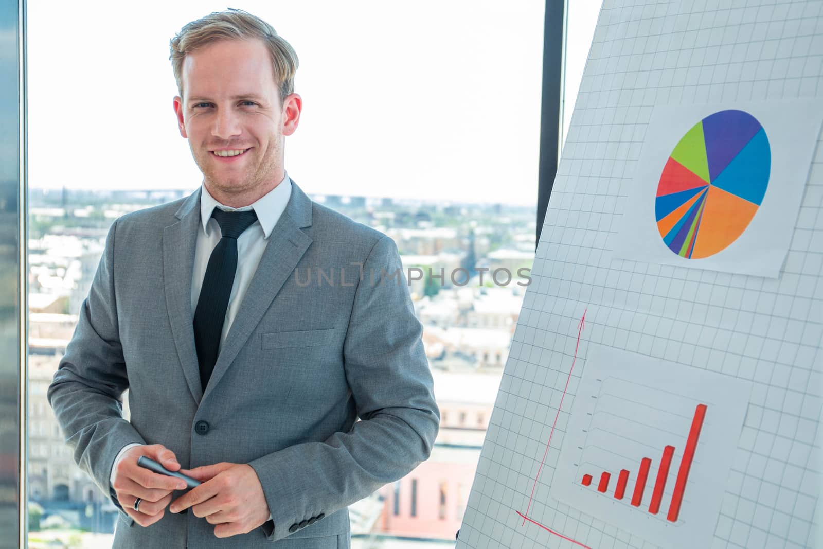 Portrait of happy smiling business man speaker standing near flipchart with diagram