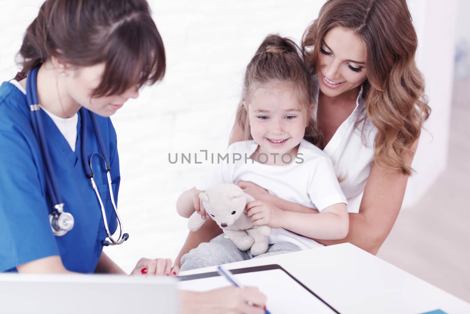 Young pediatrician doctor talking with girl and her mother