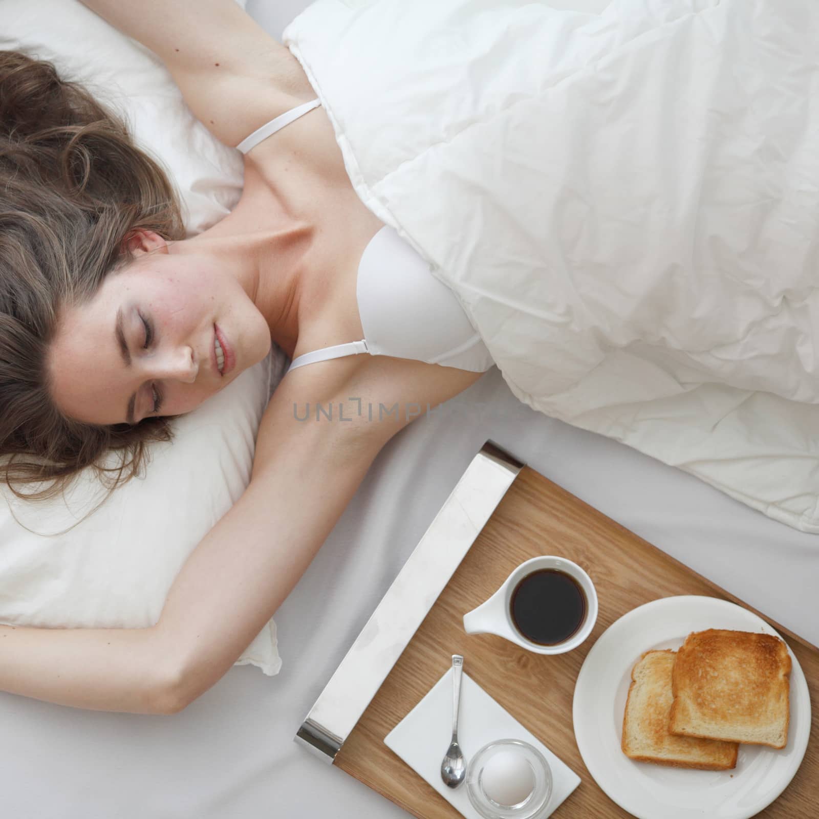 Beautiful young girl having breakfast in bed