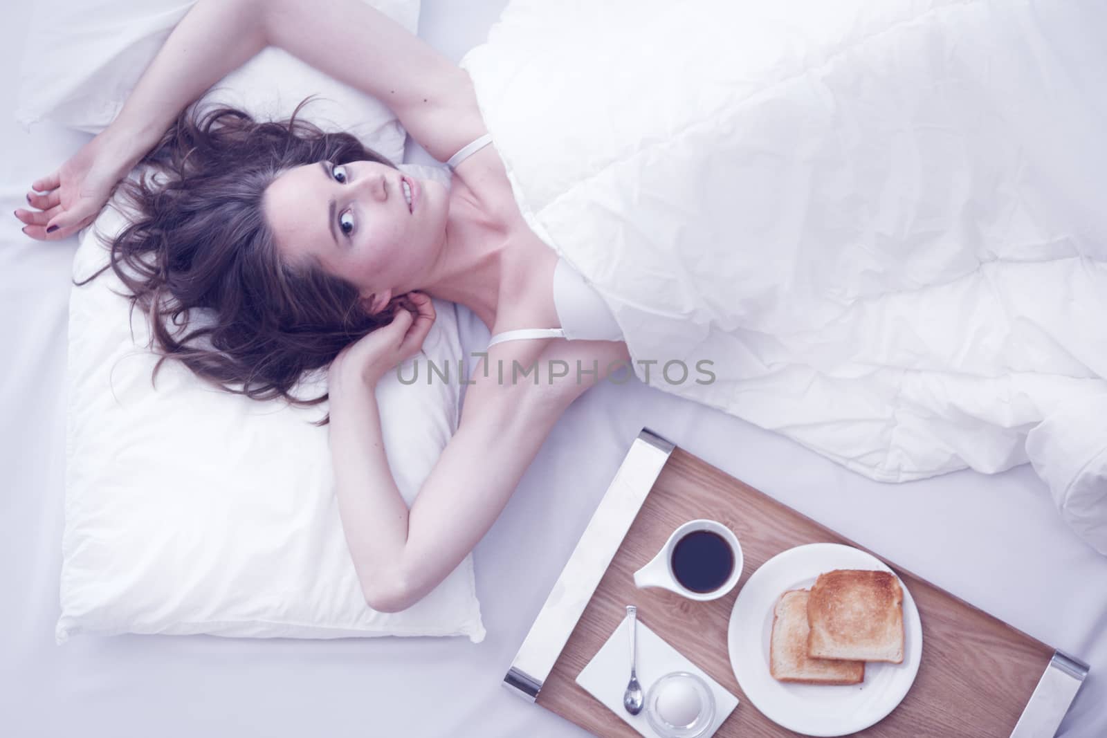 Beautiful young girl having breakfast in bed