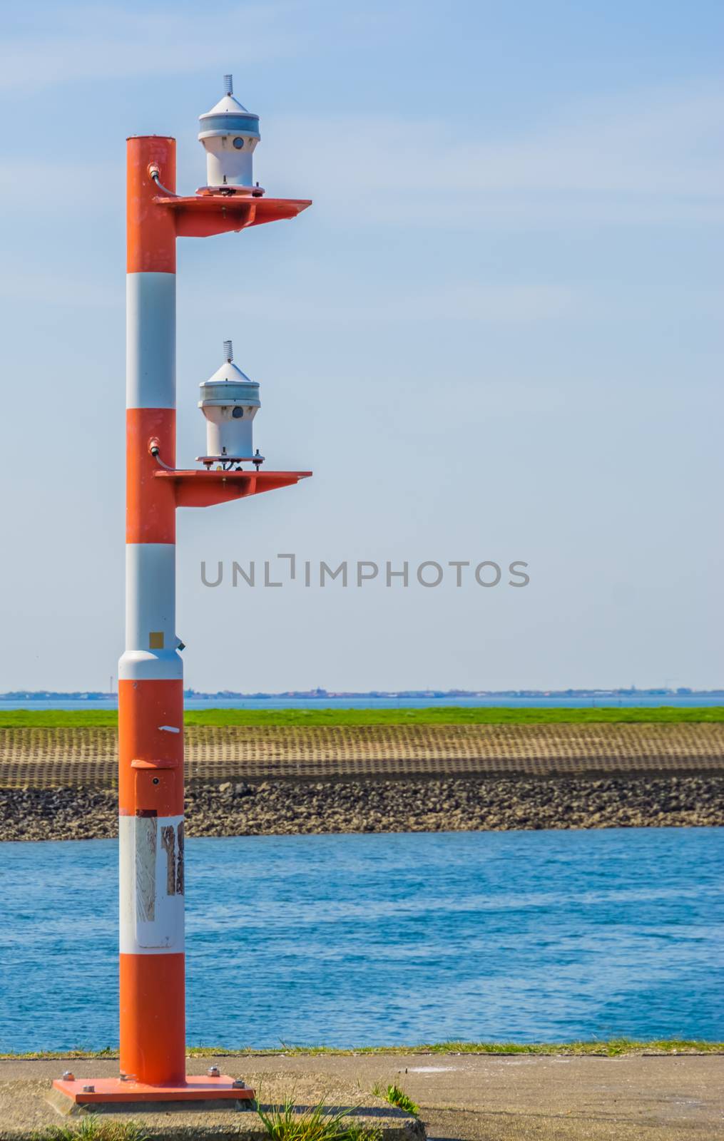 red with white striped light pole at the harbor of Tholen, lamppost for the ships by charlottebleijenberg