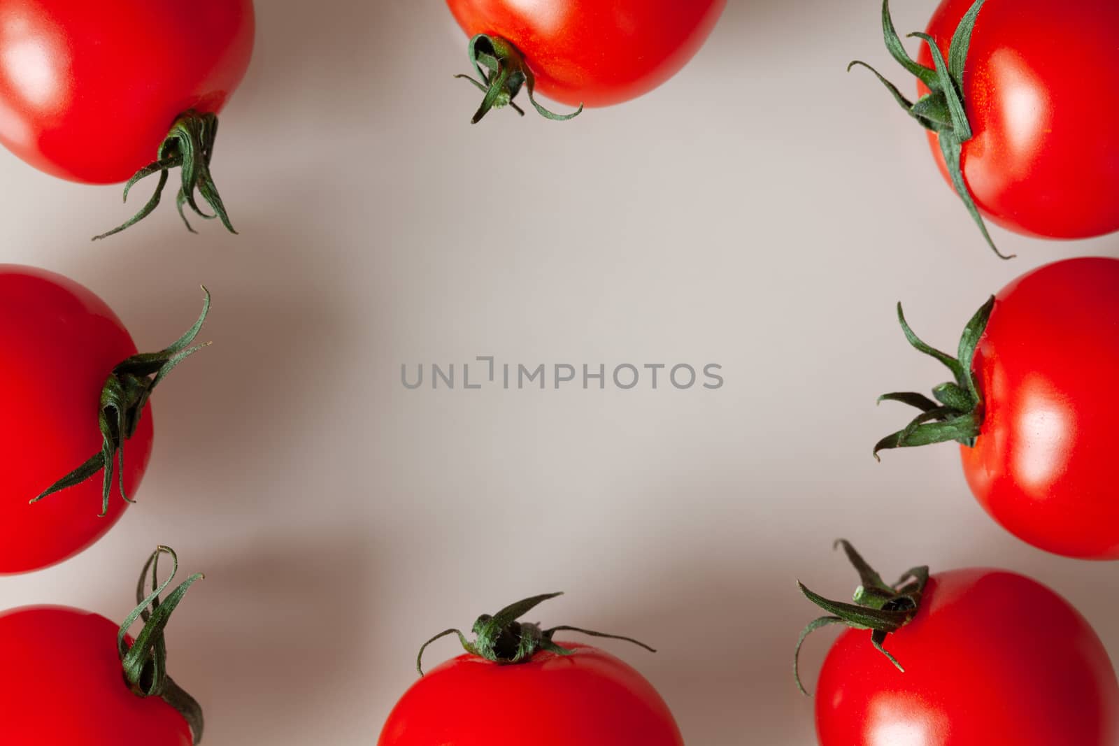 Frame of fresh cherry tomatoes on grey beige background with copy space. Macro, flat lay. Horizontal. Can be used in vertical format.