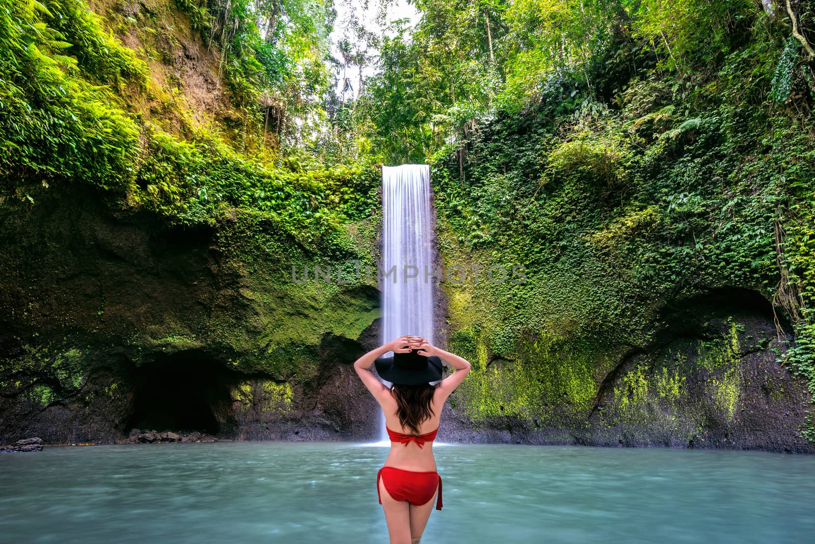 Woman standing in Tibumana waterfall in Bali island, Indonesia.