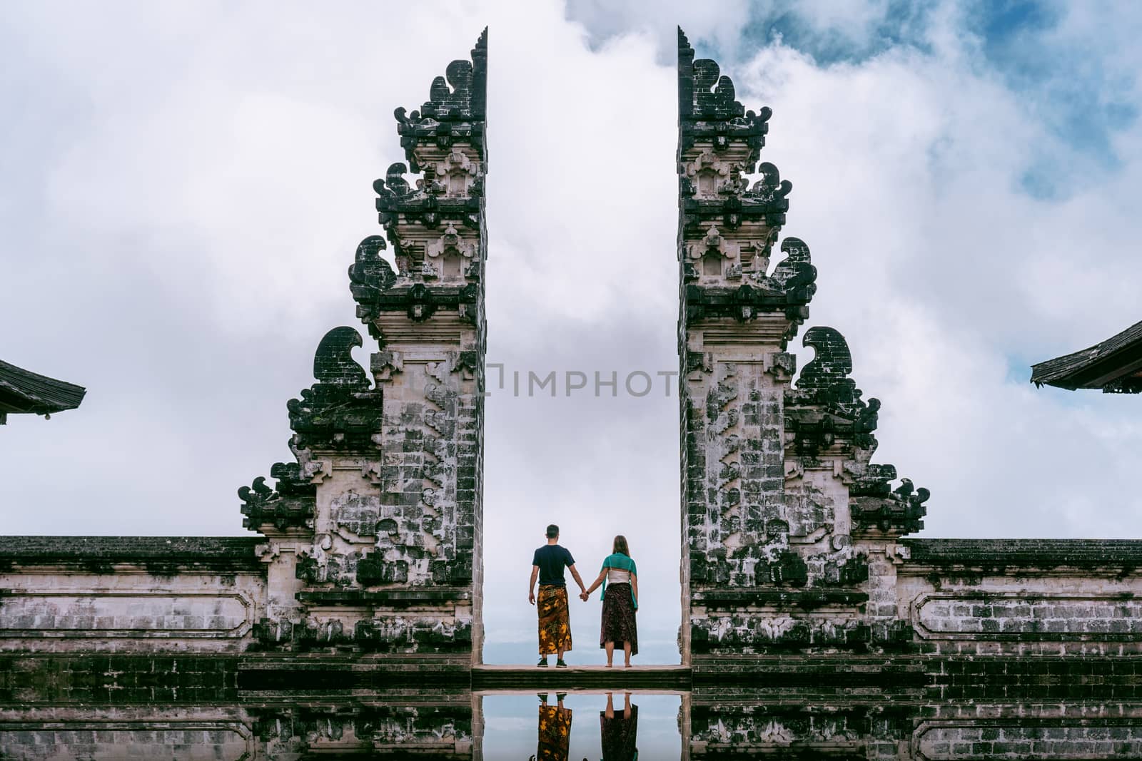 Young couple standing in temple gates and holding hands of each other at Lempuyang Luhur temple in Bali, Indonesia. Vintage tone.