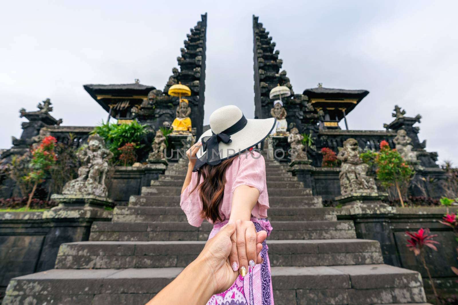Women tourists holding man's hand and leading him to Besakih temple in Bali, Indonesia. by gutarphotoghaphy