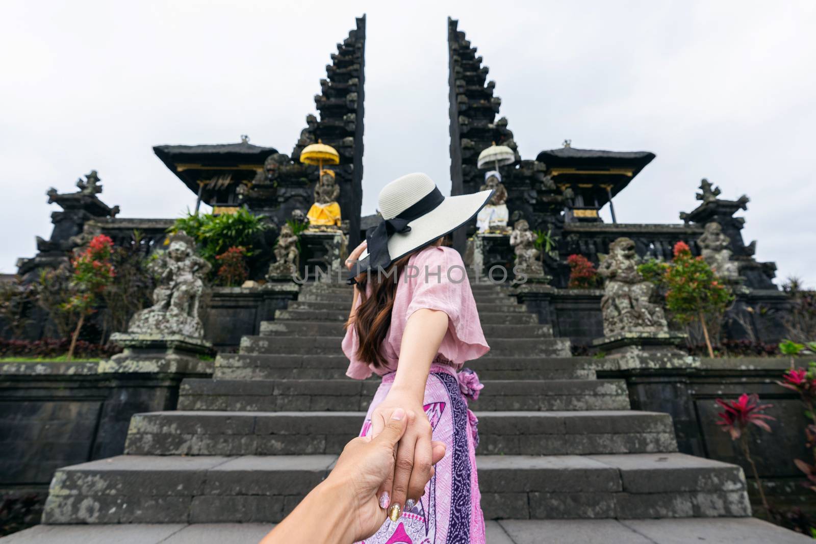 Women tourists holding man's hand and leading him to Besakih temple in Bali, Indonesia. by gutarphotoghaphy