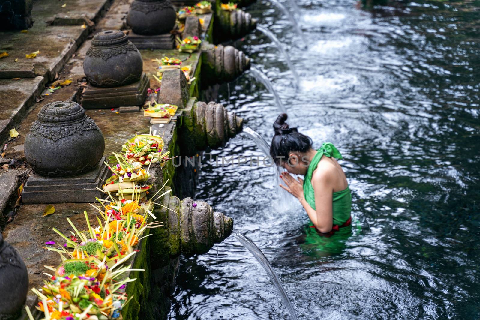 Woman pray and bath holy spring waters in Tirta Empul water temple, Bali, Indonesia. by gutarphotoghaphy